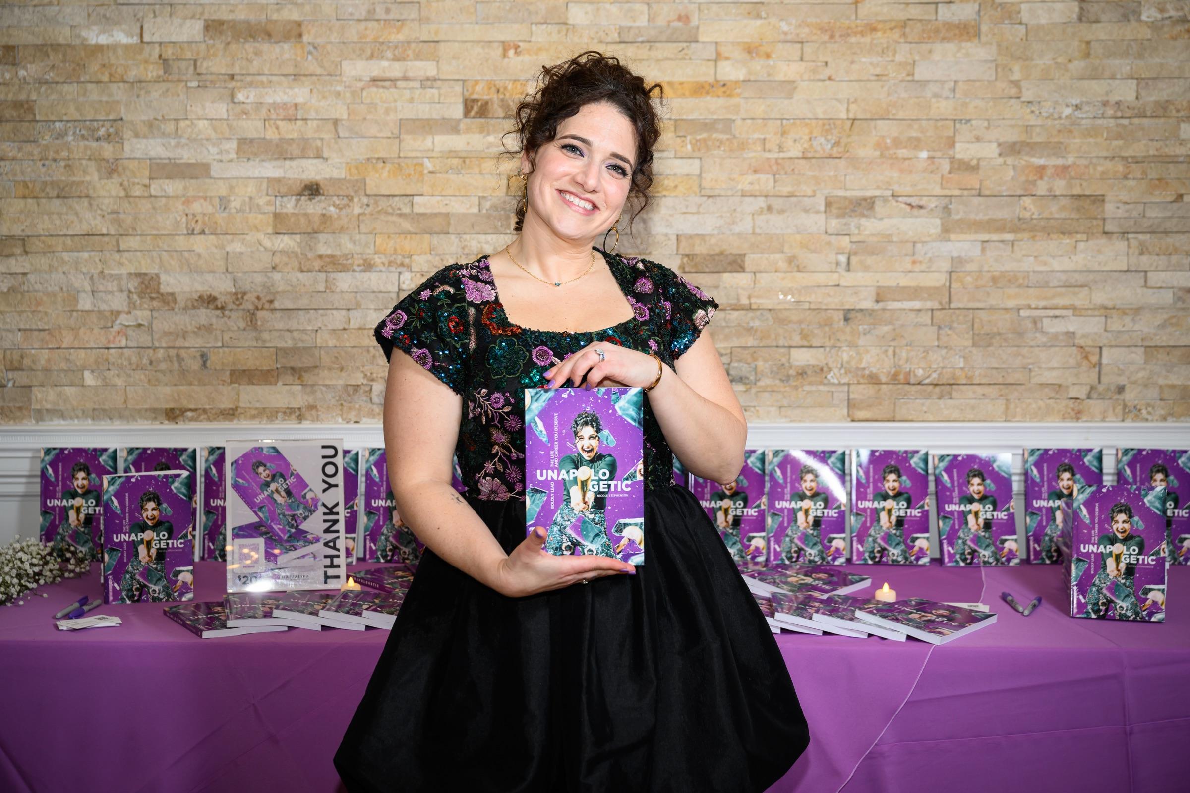 Nicole Stephenson holding up Unapologetic at her book launch event.
